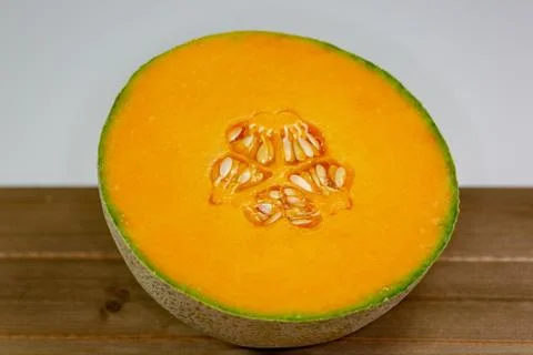 Half a cantaloup sitting on the kitchen table waiting to be eaten Stock Photos