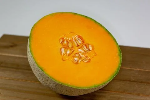 Half a cantaloup sitting on the kitchen table waiting to be eaten Stock Photos