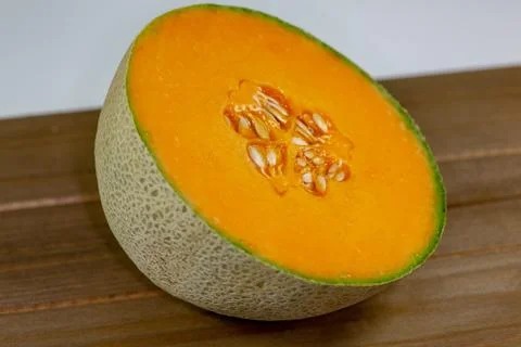 Half a cantaloup sitting on the kitchen table waiting to be eaten Stock Photos