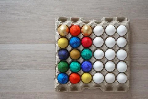 Half colored and half white eggs in square cardboard stand Stock Photos