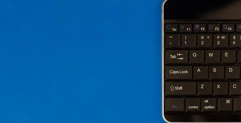 Half of a computer keyboard on a blue isolated background. Black keyboard with Foto stock