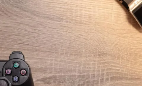 Half of a console video gaming controller on the left on wooden grey brown ba Stock Photos