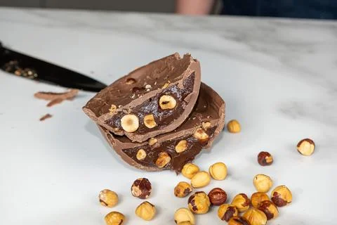 Half cut milk chocolate Easter egg filled with hazelnut cream on a marble cou Stock Photos
