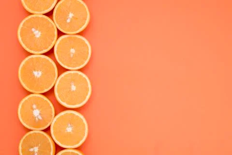 Half-cut oranges in two rows on the edge of the orange background Stock Photos