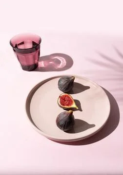 Half-cut purple fig with two whole figs on pink plate Stock Photos