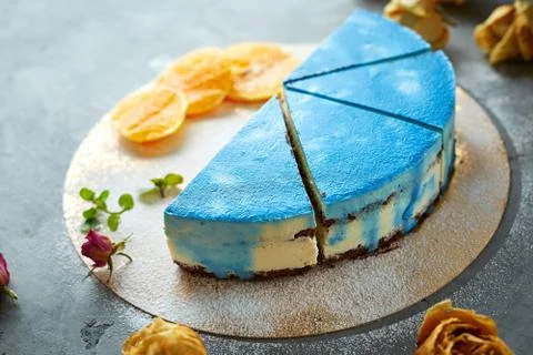 Half of cutted mousse cake with blue glaze on a dark gray concrete background Stock Photos