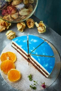 Half of cutted mousse cake with blue glaze on a dark gray concrete background Stock Photos