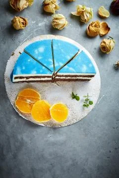 Half of cutted mousse cake with blue glaze on a dark gray concrete background Stock Photos