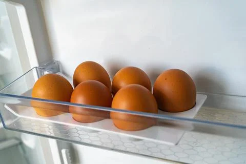 Half a dozen eggs in the refrigerator tray. 6 brown chicken eggs Stock Photos