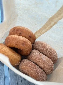 Half dozen of mixed classic plain and sugar cinnamon donuts in paper bag Stock Photos