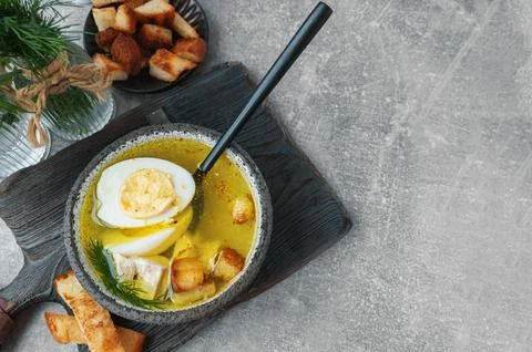 Half an egg in a spoon served with chicken or turkey broth. Broth with egg and Stock Photos