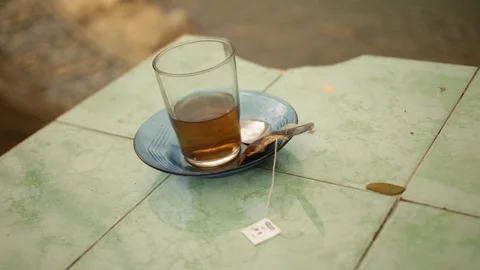 Half empty cup of tea sits next to river bank in the daytime in Indonesia Stock-Footage 107655198