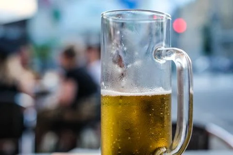 Half empty glass of light beer in a pub. Selective focus Stock Photos