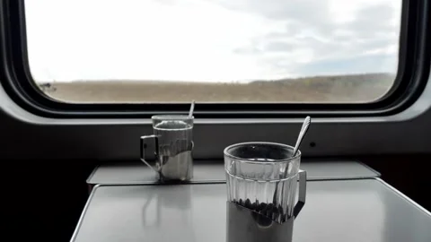  half-empty glass of tea in a cup holder stands on a table on a train Stock Footage 272290528