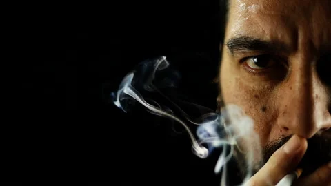 Half face portrait of concentrated man smoking cigarette and looks to camera Stock Footage 157486625