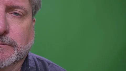 Half face portrait of senior gray haired man watches miserably isolated on green Video stock 108684768