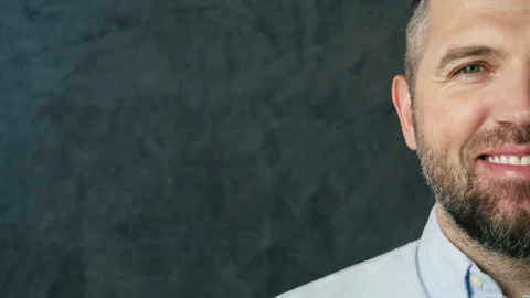 Half face of positive smiling bearded man looking at camera on grey background Video stock 267057074