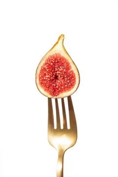 Half fig on a fork with vibrant red interior Stock Photos