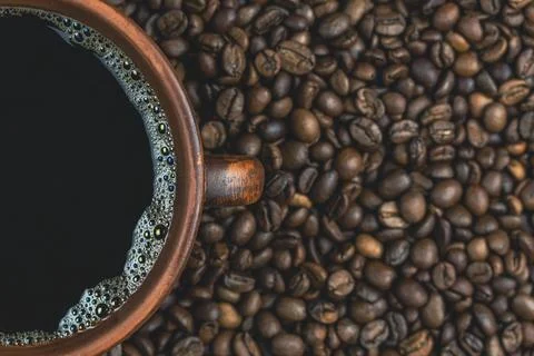 Half-filled coffee cup on a bed of roasted coffee beans Stock Photos