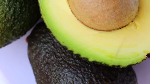 Half a fresh avocado with pit, rotation in circle. cut avocado close-up Stock Footage 253178476