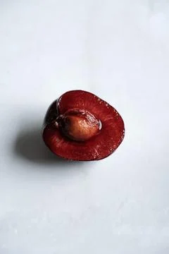 Half of fresh sweet cherry with pit on white marble background with copy spac Stock Photos