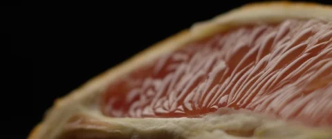 Half a grapefruit lies on a dark surface in darkens, then comes to light. Stock Footage 106002321