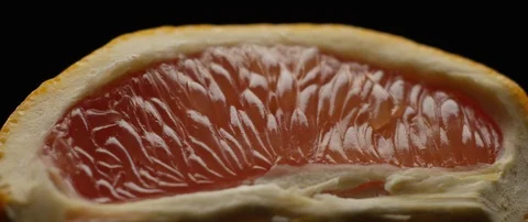 Half a grapefruit lies on a dark surface in contrasting light Stock Footage 106011670