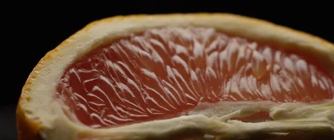 Half a grapefruit lies on a dark surface in contrasting light Stock Footage 106011675