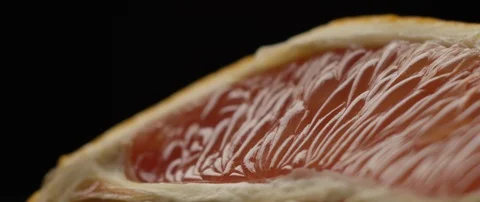 Half a grapefruit lies on a dark surface in darkens, then comes to light Stock Footage 106011957