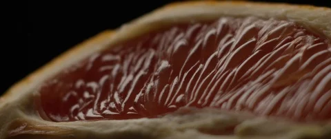 Half a grapefruit lies on a dark surface in darkens, then comes to light Stock Footage 106011963