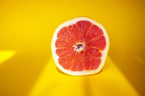 Half of grapefruit on orange background Stock Photos