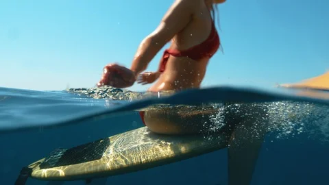 HALF HALF: Unrecognizable surfer sits on her board while waiting for new waves Stock Footage 127420106