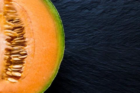 Half of Hami Melon Fruit on Black Stone Background Surface with Free Space Stock Photos