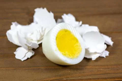 Half a hardboiled egg with the shells laying on the kitchen table Stock Photos