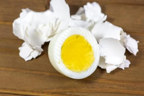 Half a hardboiled egg with the shells laying on the kitchen table Stock Photos