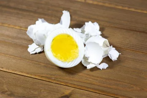 Half a hardboiled egg with the shells laying on the kitchen table Stock Photos