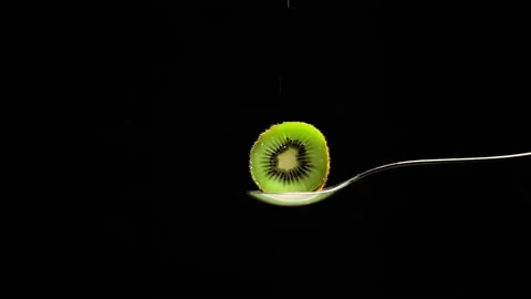 Half kiwi on black background sprinkled with white sugar in slow motion Stock Footage 131406267