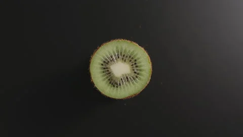 Half of a kiwi rotates on a black surface. Top view. Stop motion Vídeo Stock 131588634
