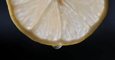 Half a lemon on a black background with several drops of juice falling Stock Footage 144829391