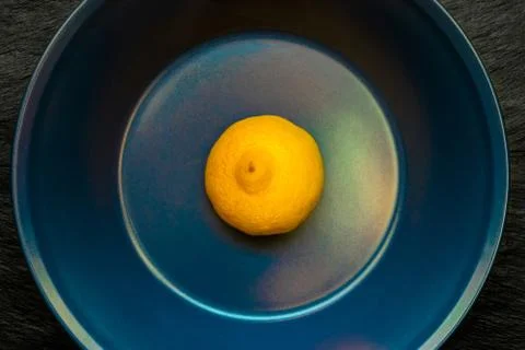 Half of Lemon in Blue Plate Which Placed on Black Stone Surface Stock Photos