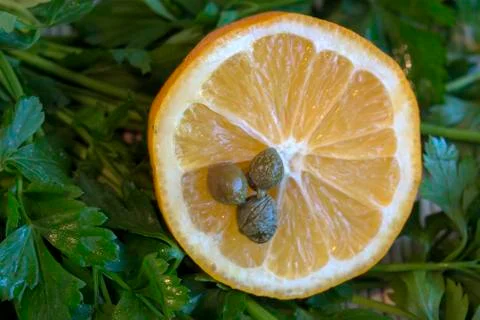 Half a lemon with capers. Stock Photos
