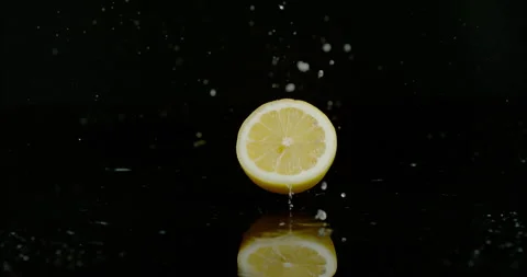 Half of Lemon falls onto black background splashing water 스톡 동영상 249614689