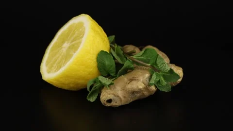 Half lemon, ginger root and sprigs of mint rotates on a black background. Видео 152069086