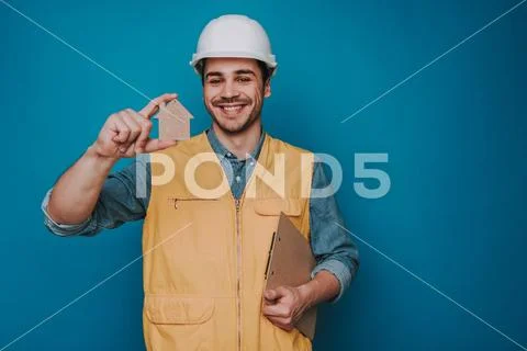 Half length of happy guy wearing helmet and vest on blue background Stock Photos