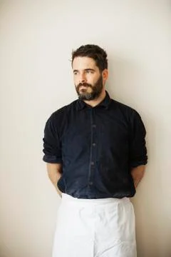 Half length portrait of a bearded man wearing a white apron. Stock Photos