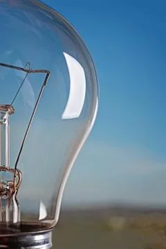Half light bulb on a background of blue sky and mountains. Stockfoto's
