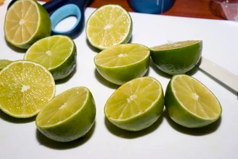Half of the lime and lime slices are lying on the white wooden background. Ci Stock Photos