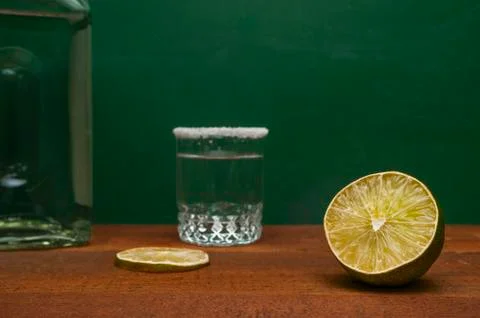 Half Of A Lime With Blurred Lime Slice, Silver Tequila Shot Rimmed With Salt Stock Photos