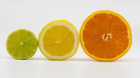 Half a lime, lemon and orange next to each other in front of a white backgrou Stock Photos