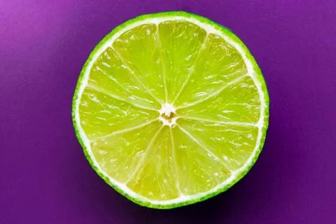 Half of Lime Placed on Purple Background Surface Stock Photos